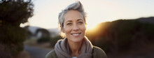 Lifestyle portrait of happy woman with short gray hair walking alone on park trail outside