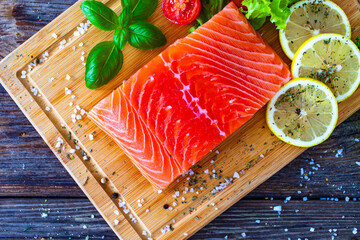 Poster - Fresh raw salmon steak with salt and fresh vegetables on wooden background
