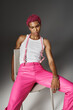 © LIGHTFIELD STUDIOS - handsome stylish man in pink pants with suspenders posing on chair on gray backdrop, fashion concept