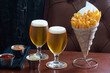 Golden French Fries in a Wire Cone with Two Belgian Beers and Ketchup, Mayonnaise, and Chile Dipping Sauces in a Bar