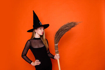 Sticker - Photo portrait of pretty blonde teenager girl hold broom pouted lips dressed black halloween outfit isolated on orange color background