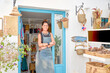© Javier - Front view of  Hispanic female owner of a small souvenir business posing proudly at the door of her business. She is looking at camera and smiling.