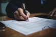 A person is pictured signing a document with a pen. This image can be used to represent the act of signing important paperwork or contracts.