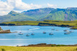 The beautiful Isle of Canna, Inner Hebrides in Summer with yachts and a catamaran in the bay and a RIB speeding towards the harbour with the Isle of Rum in the background.  Horizontal.  Copy space