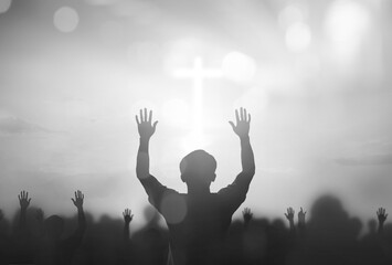 Wall Mural - silhouette human raising hand to praying god on blurred white cross with bokeh background