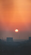 © Fauren - Passing plane over Amsterdam dives into the solar disc during sunset. Travelling in modern times. City immersed in smog and an orange sky