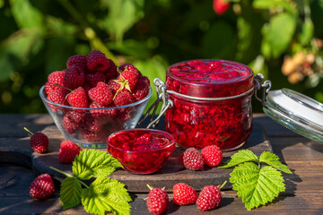 Wall Mural - Red raspberry jam and fresh raspberry on a rustic wooden table outdoors near garden. Rustic style, closeup