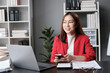 © Parichat - Happy young Asian business woman with a smile using smartphone at the office.