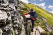 © Guzel - Gray-haired long-haired man with backpack climbing up the slope to the summit through Sala with railing, Austria