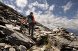 © Guzel - Man with backpack standing on rocky trail against picturesque sky background and looking down into valley, Austria