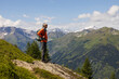 © Guzel - Gray-haired long-haired man standing on rock ledge and looking at stunning mountain view with snow-capped peaks, Austria