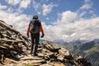 © Guzel - Gray-haired man climbing up on rock slabs against the backdrop of a picturesque sky and a mountain range