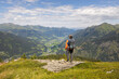 © Guzel - Gray-haired long-haired male hiker with backpack standing at the edge of cliff and looking at a mountain valley, Austria