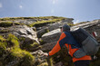 © Guzel - Gray-haired man with a big backpack standing by a rocky trail and looking at the further route, Austria