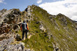 © Guzel - Man with backpack climbing steep rocky trail up to summit marked with cross, Austria