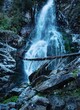 a tall waterfall cascading down around frozen rocks