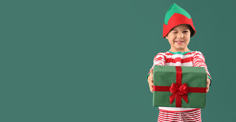 Sticker - Cute little boy in elf costume and with Christmas gift on green background with space for text