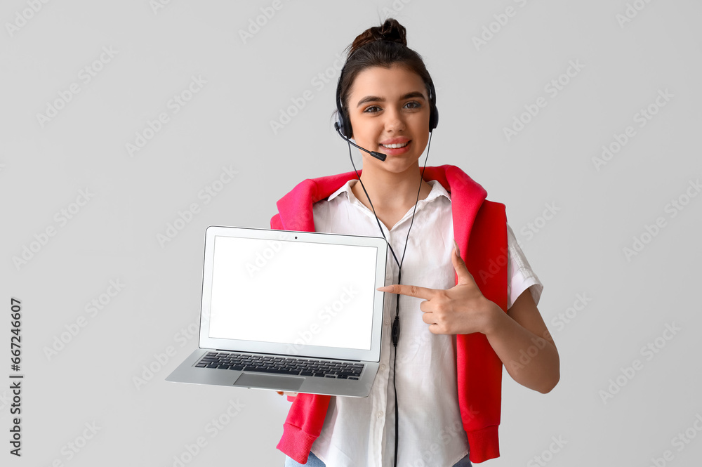 Female technical support agent with laptop on light background