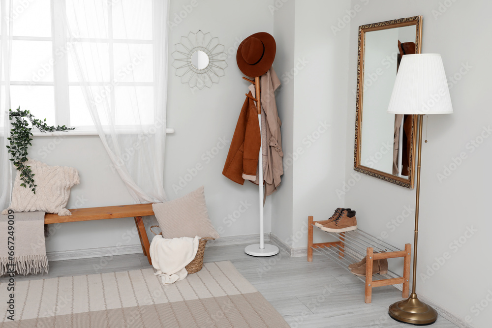 Interior of light hallway with mirror, rack and shoes stand