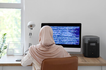 Muslim female programmer working in office, back view