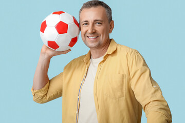 Poster - Handsome mature man with soccer ball on blue background