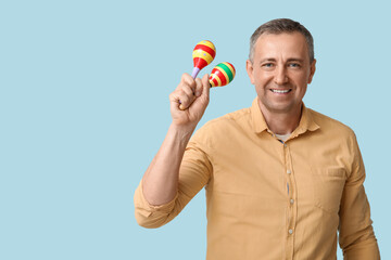 Canvas Print - Handsome mature Mexican man with maracas on blue background