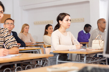 Sticker - Young woman sitting at desk in classroom working during lesson at adult education class