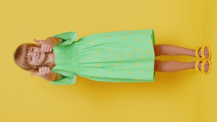 Wall Mural - Like. Happy preteen child girl kid looking approvingly at camera showing thumbs up, like sign positive something good, positive feedback great news. Children isolated on yellow background. Vertical