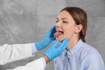 Canvas Print - Doctor in medical gloves examining woman`s oral cavity indoors, closeup