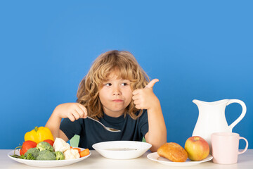 Wall Mural - Child eating soup. Children eat breakfast. Small kid eating a soup. Boy eating soup for dinner.