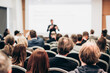 © kasto - Speaker giving a talk in conference hall at business event. Rear view of unrecognizable people in audience at the conference hall. Business and entrepreneurship concept