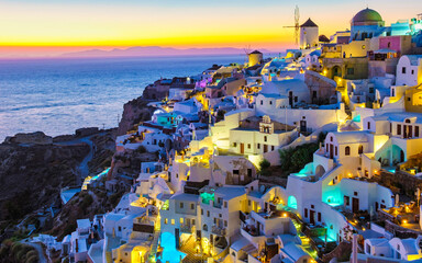 Wall Mural - White churches an blue domes by the ocean of Oia Santorini Greece, a traditional Greek village in Santorini at sunset, evening view with lights at the pools of the many hotels of Santorini