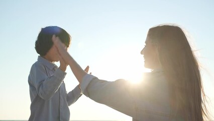 Canvas Print - Mother and son playing outdoors at sunset, low angle view