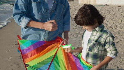 Canvas Print - Mother and her son playing with kite on beach near sea