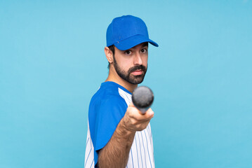 Wall Mural - Young man playing baseball over isolated blue background