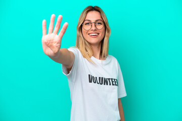 Wall Mural - Young volunteer Uruguayan woman isolated on blue background happy and counting four with fingers