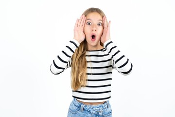 Wall Mural - Beautiful teen blonde girl  with scared expression, keeps hands on head, jaw dropped, has terrific expression. Omg concept