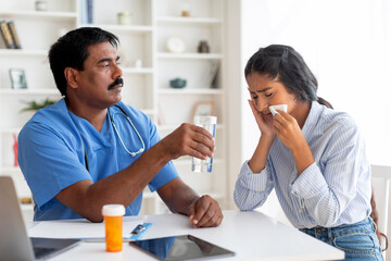 Indian doctor man comforting upset female patient crying during appointment in clinic