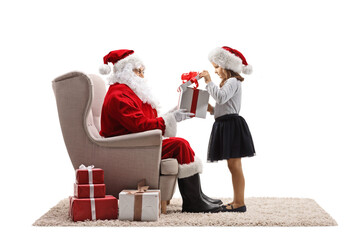 Poster - Impatient girl opening a present box in front of santa claus seated in an armchair