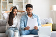 © Prostock-studio - Young Indian couple reacts to shocking document at home