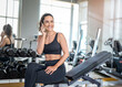 © Chutipon - Cheerful sporty woman using phone after fitness workout in gym. Young smiling woman athlete using cell phone at gym.Beautiful fit girl with smartphone at fitness centre.
