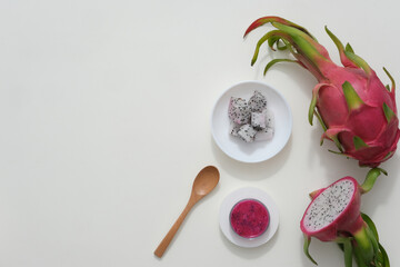 Sticker - On a white background, half of the frame is adorned with fresh dragon fruit, a white plate, and a petri dish, while the other half is left empty for text design and additional image insertion.