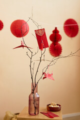 Minimal background image of tree branches decorated with paper cranes and red envelopes as Chinese New Year tradition Have overflowing abundance every year