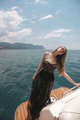 Wall Mural - beautiful woman with blond hair in luxurious black dress relaxing on the yacht in the Mediterranean sea