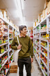 © Austockphoto - Man holding tote bag walking down supermarket aisle