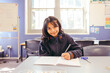 © Austockphoto - Girl student sitting at her desk in a classroom doing her schoolwork