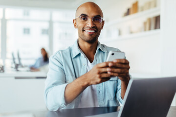 Poster - Business man using a smartphone while sitting with a laptop