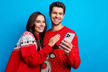 Poster - Photo portrait of lovely young spouses hugging hold device ecommerce dressed x-mas ornament red sweaters isolated on blue color background