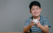 Asian boy saving money puts coins in piggy bank, Save money and finance concept, Saving money for the future