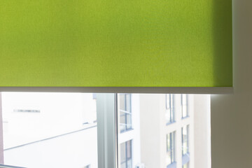 Leinwandbilder - Details of green fabric roller blinds. Automatic curtain close-up on the window. Selective focus. Motorized shades. City outside the window.